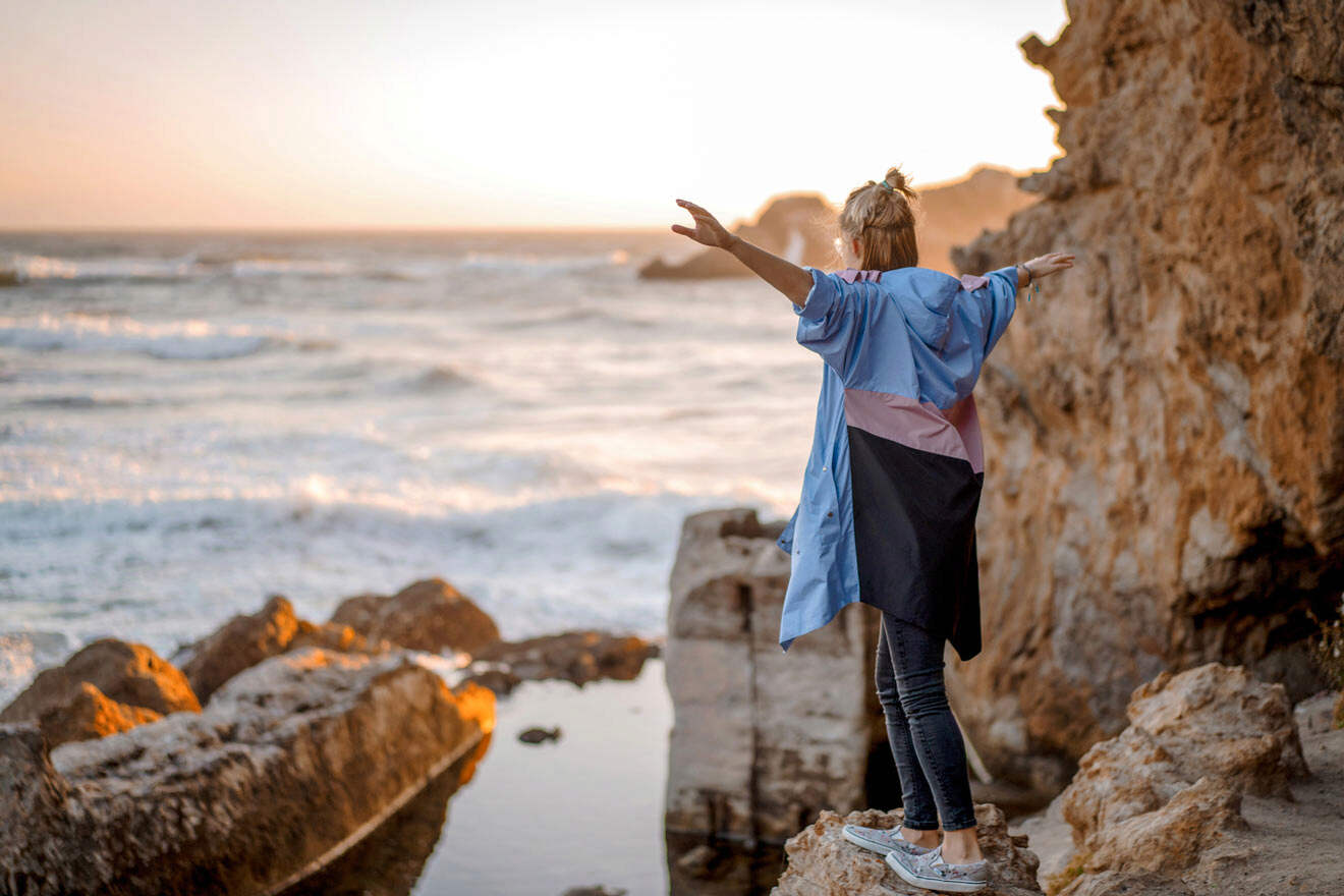 a woman standing on a rock next to the ocean