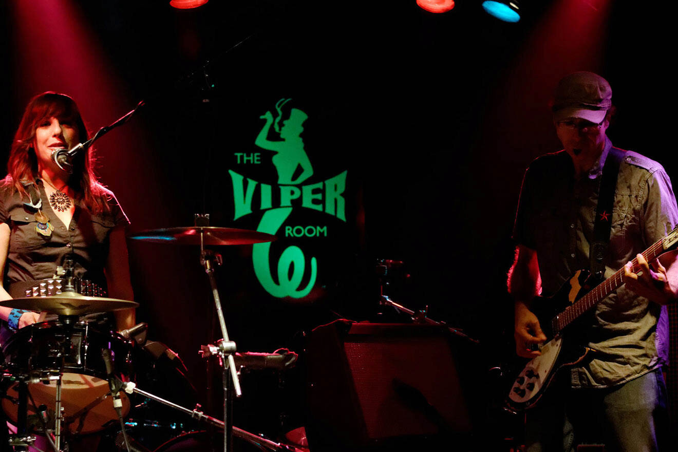 a man playing guitar and a woman playing the drums on stage