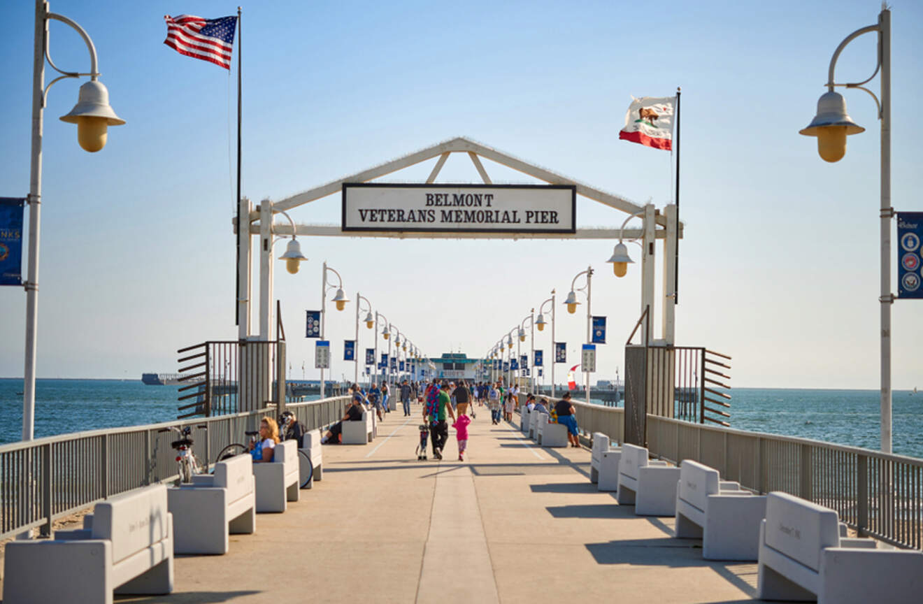 a group of people walking down a pier next to the ocean