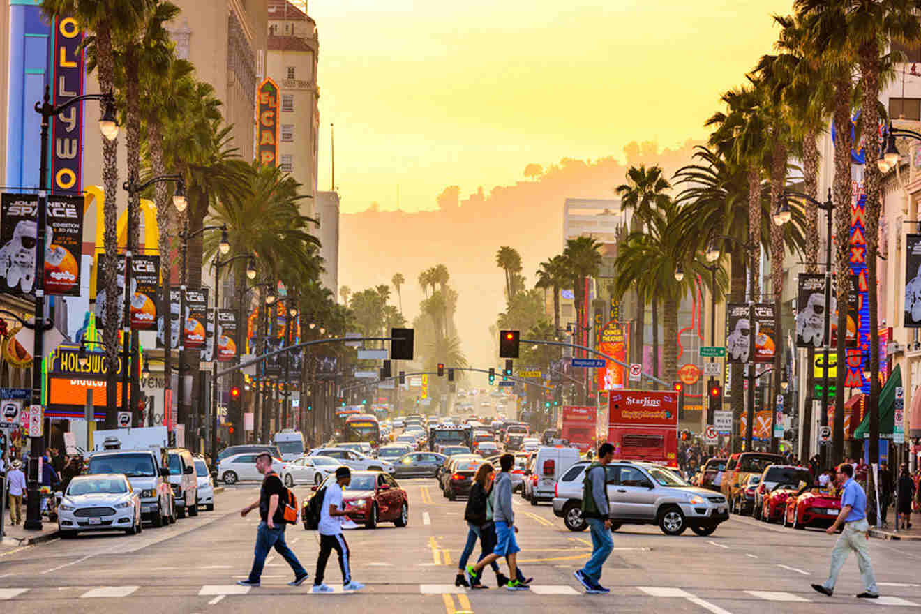 A lively view of Hollywood Boulevard in Los Angeles at sunset, with people crossing the street. 