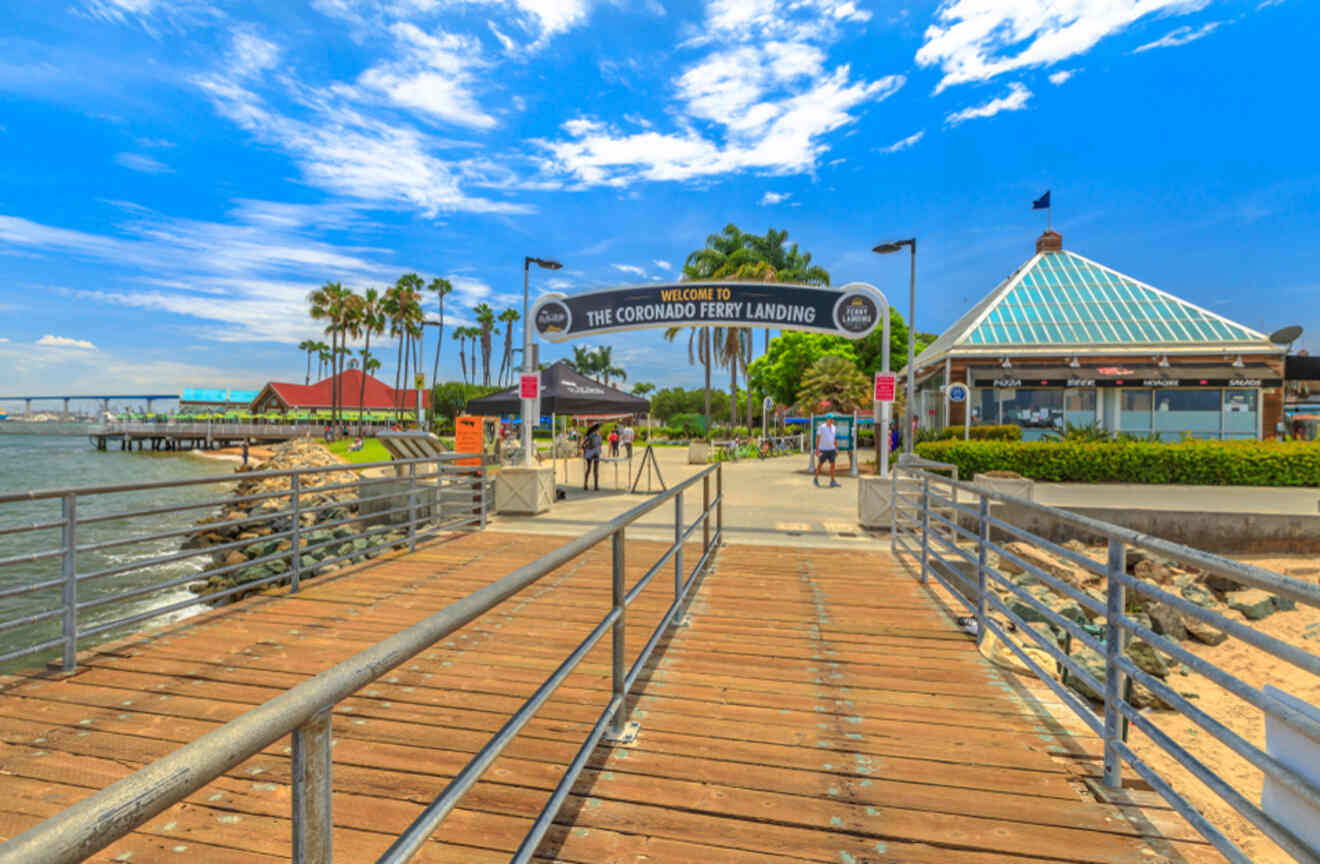 a boardwalk with people walking on it next to a body of water