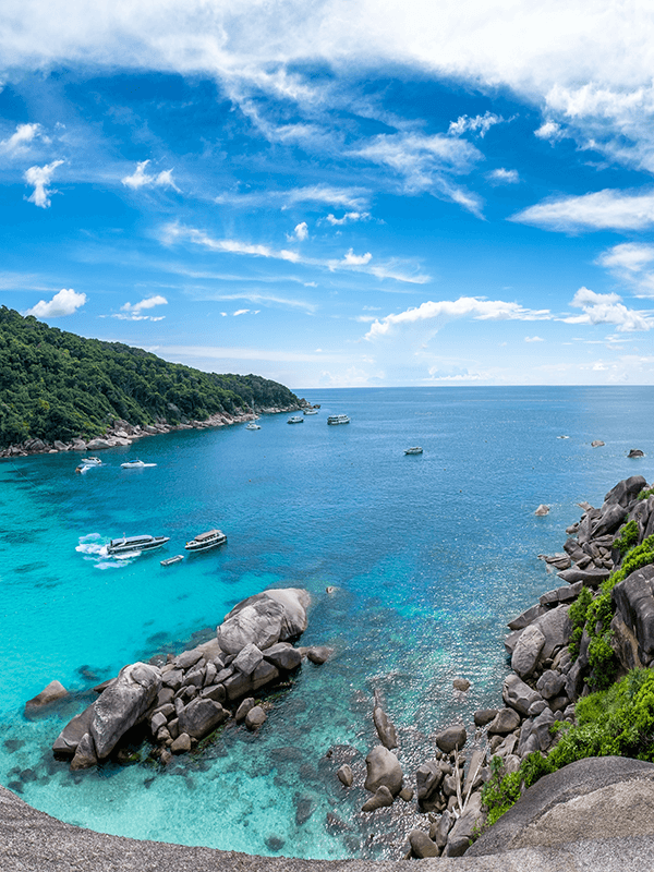 a beach with rocks in it and boats