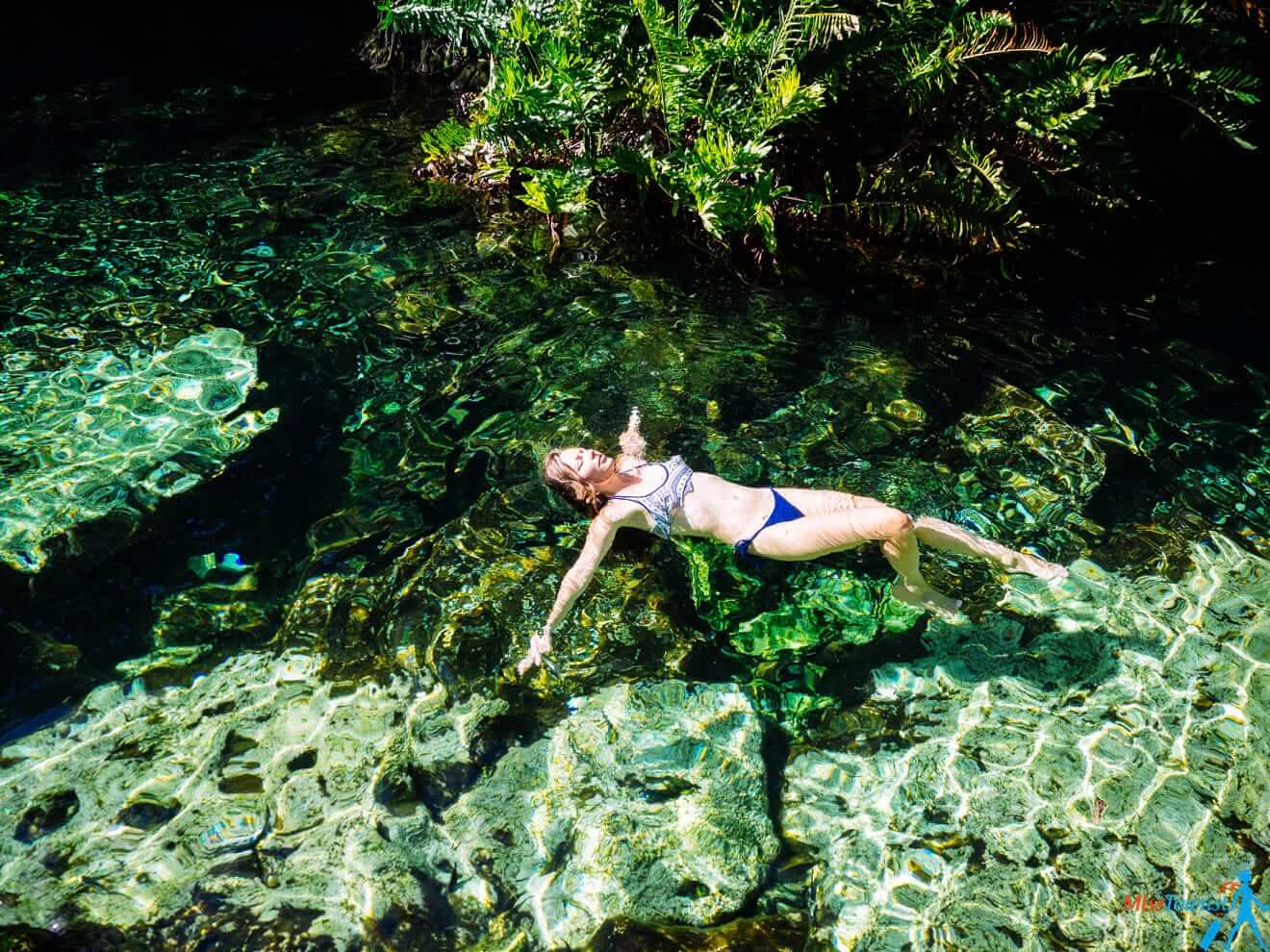 a woman in a bikini swimming in clear water