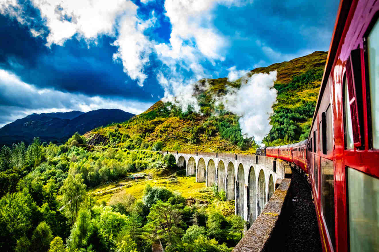 a train traveling over a bridge on top of a lush green hillside