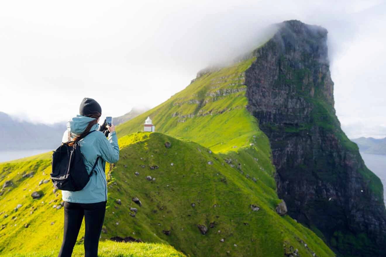 a woman taking a picture of a green mountain