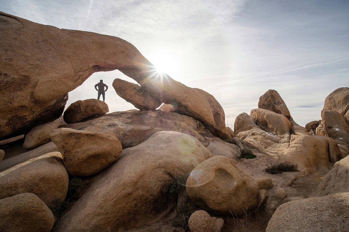 a man standing in the middle of a large rock formation in the shape of an arch