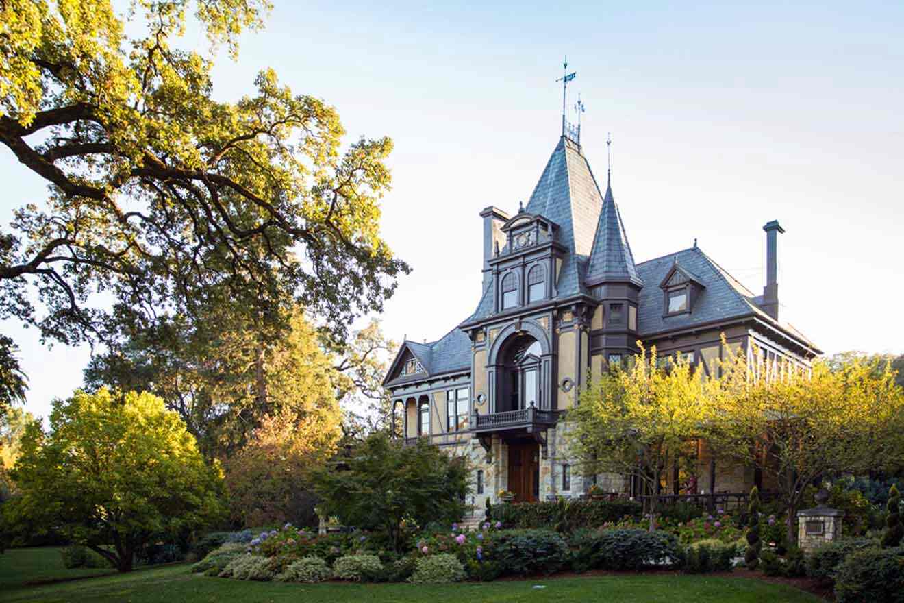 a large house with a tower on top of it surrounded by greenery and flowers