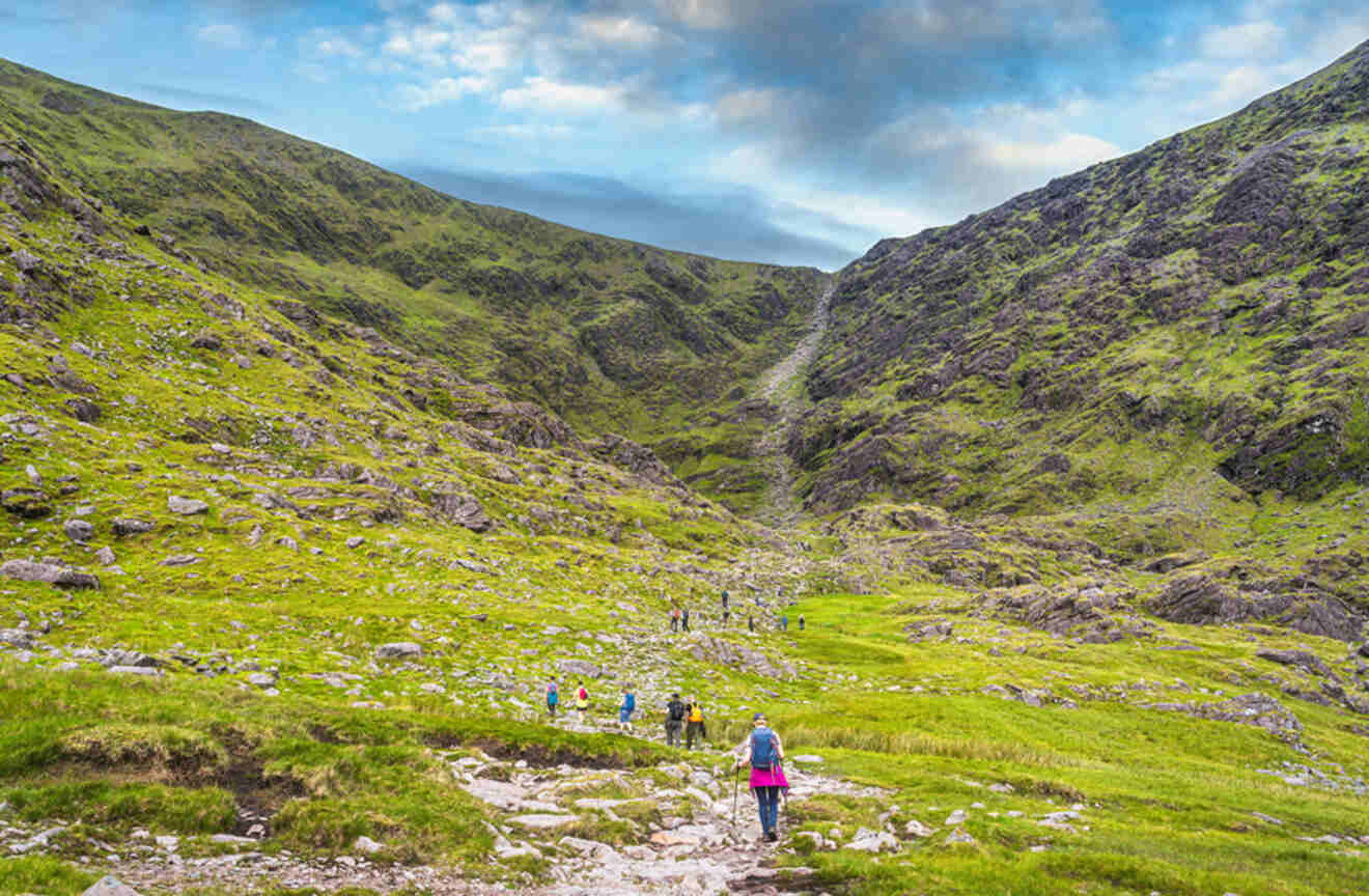 a group of people hiking up a grassy hill