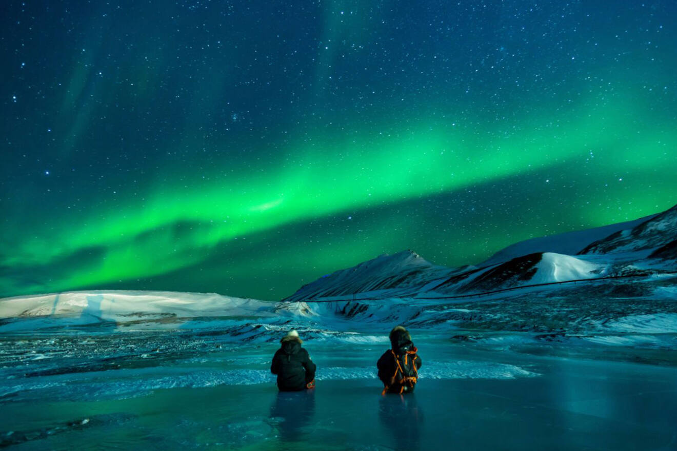 Two people sitting and looking at the northern lights