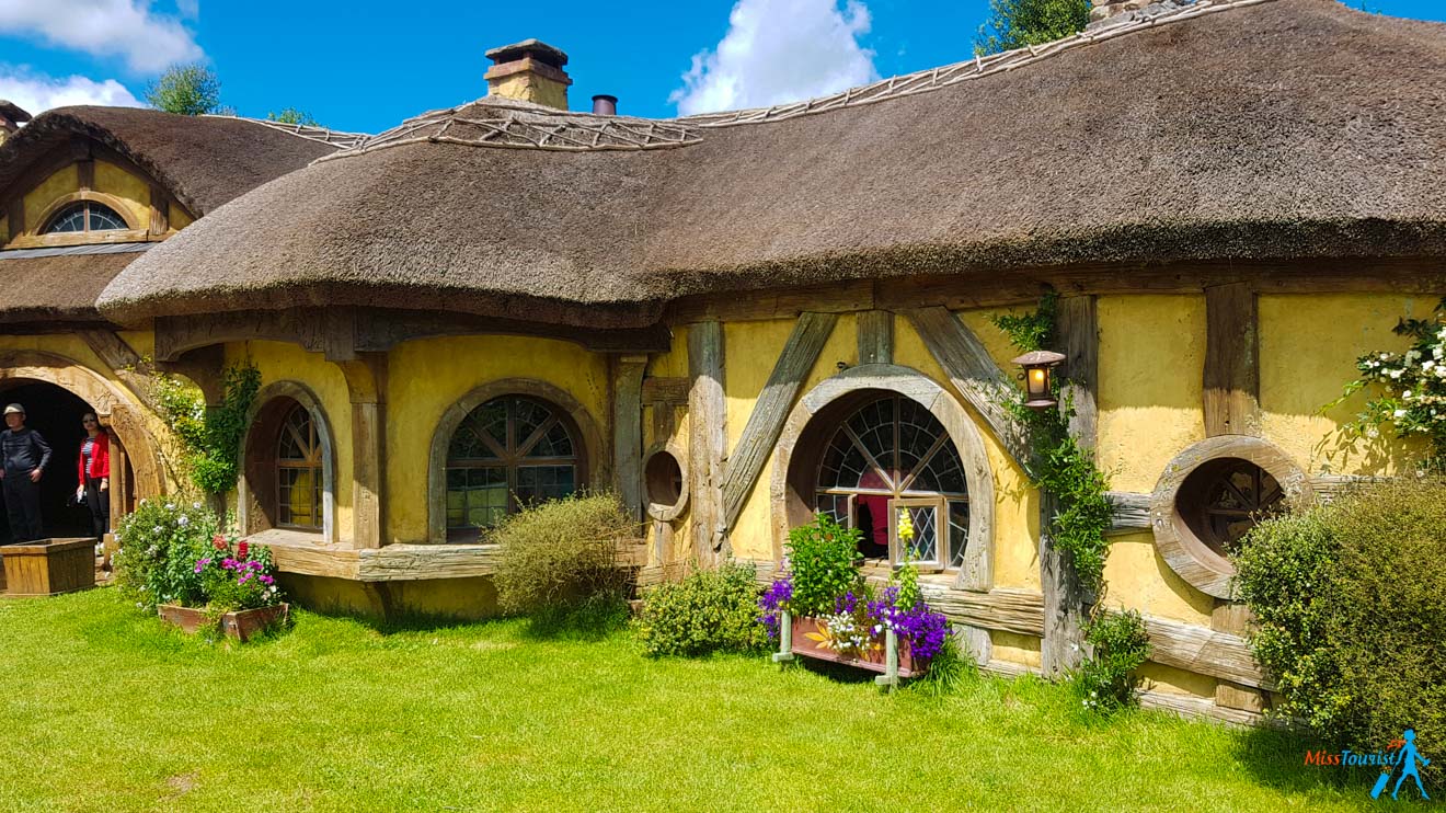 a yellow house with a thatched roof and windows