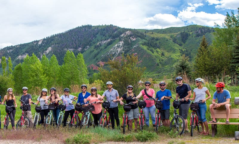 group of people standing next to bikes posing for photo