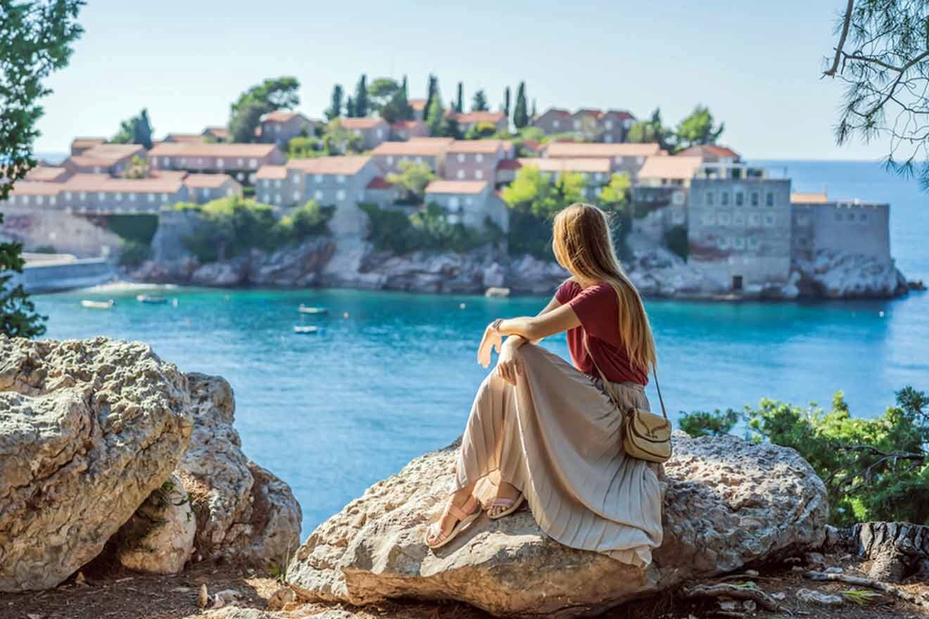 a woman sitting on a rock looking out over the water