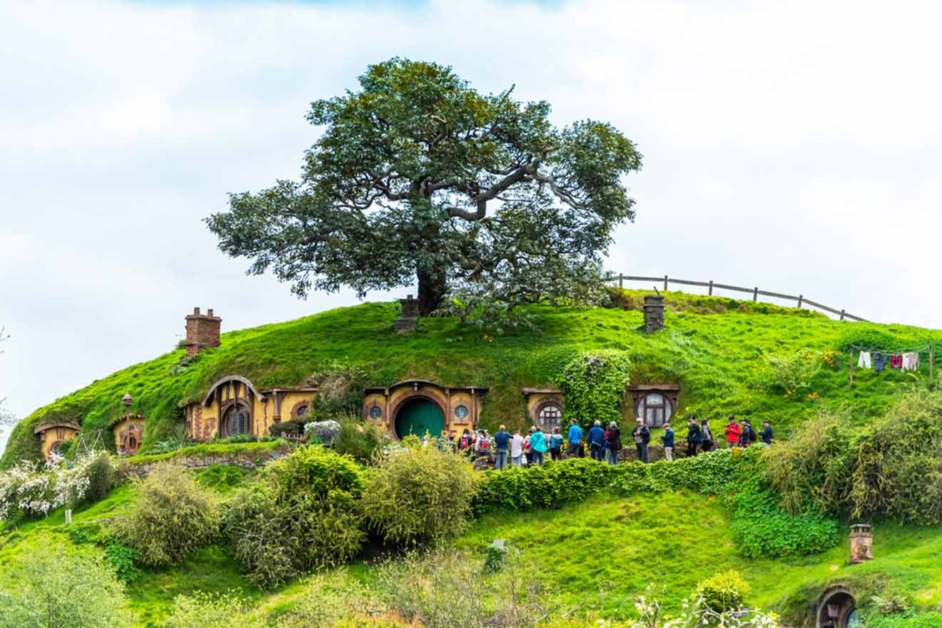 a group of people standing in front of a hill with small houses