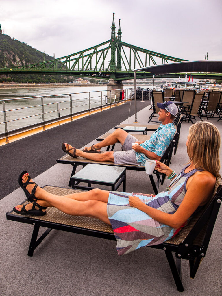 two people sitting in sun chairs drinking coffee