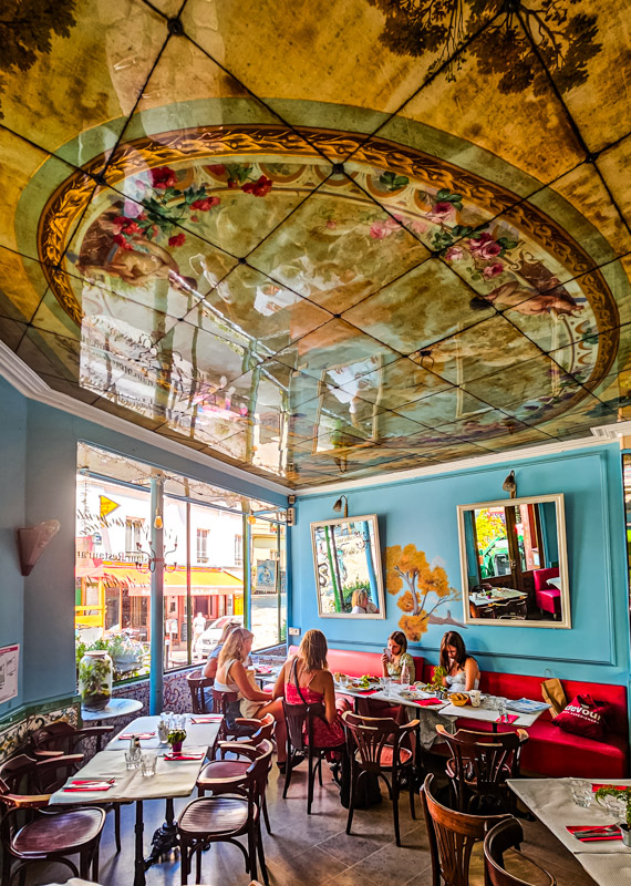 people sitting at table in L'été en pente douce restaurant with bright blue walls and painted roof