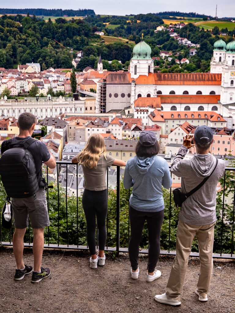 Four people standing against a fence with elevated view of a city