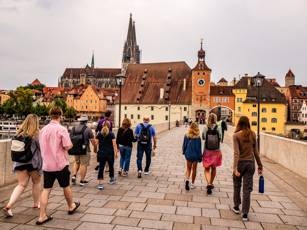 People walking across a bridge towards a city