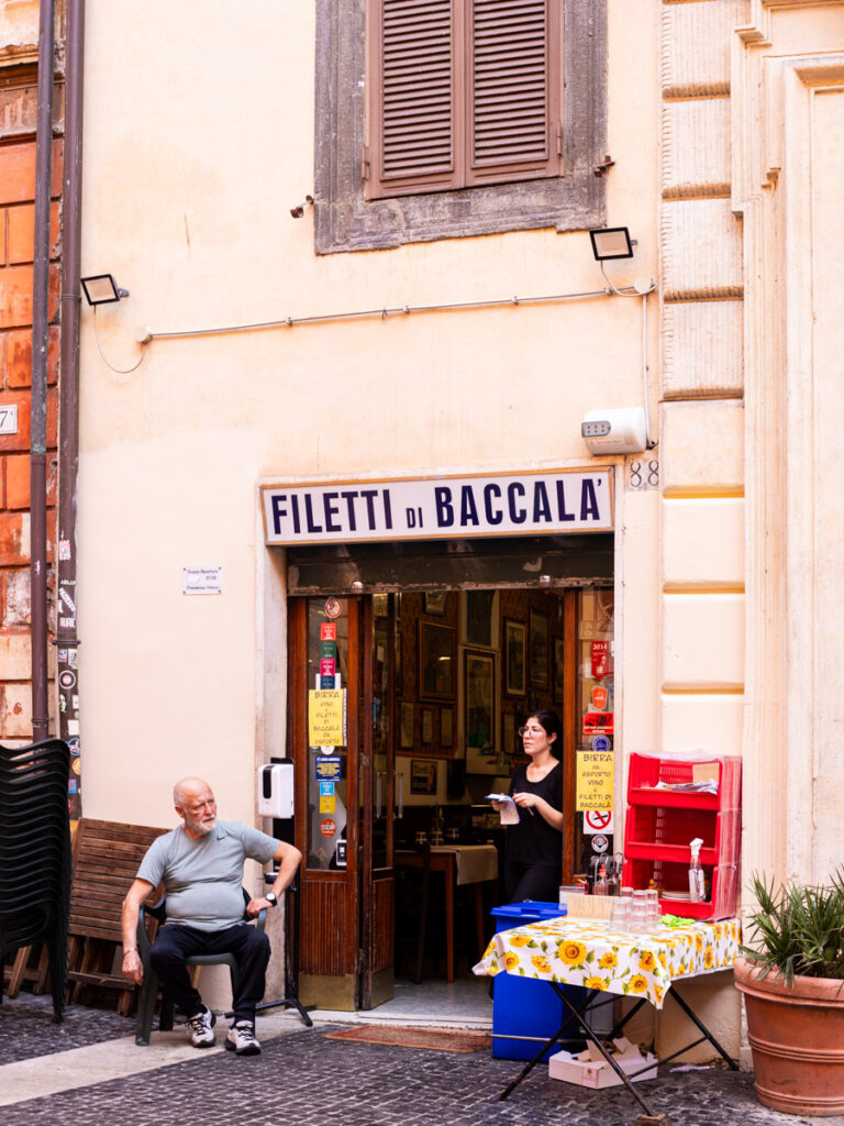 man and woman standing outside fried cod snack shop in rome