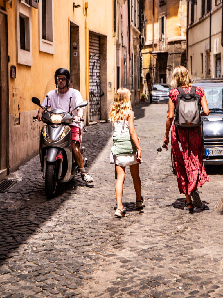 Two females walking and a man on a motor bike