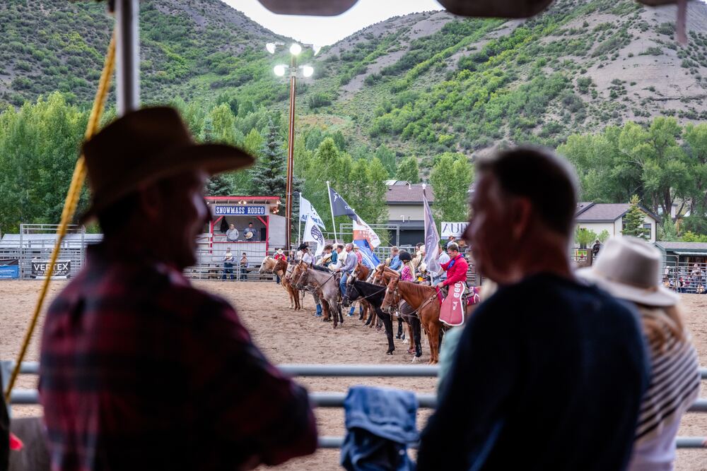 people riding horses carrying flgs at rodeo