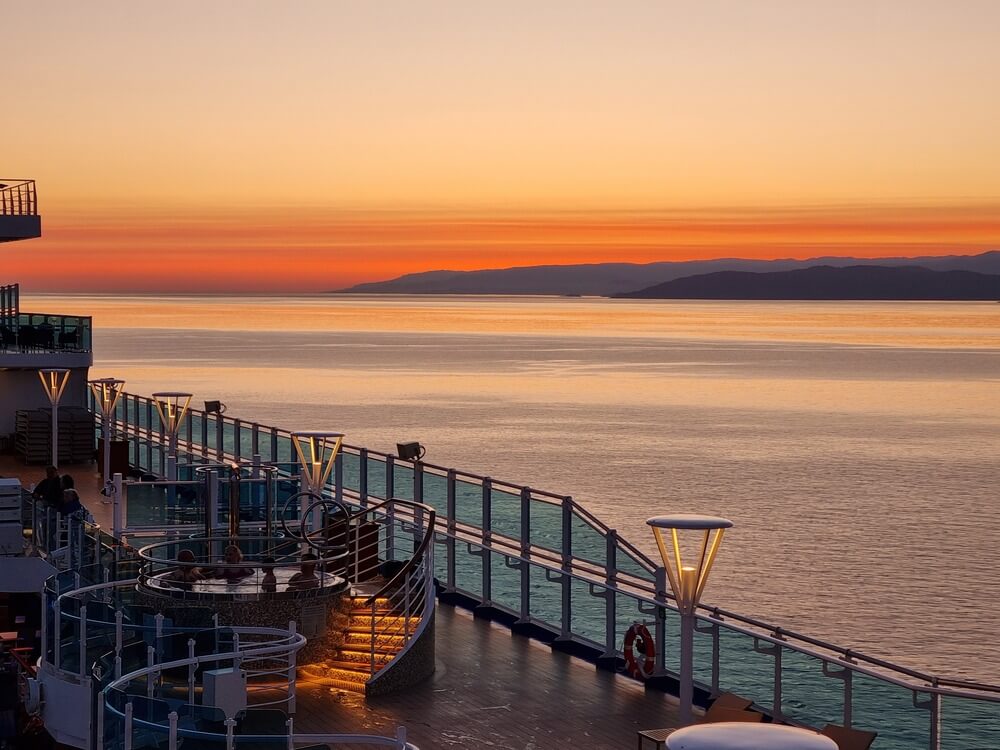 cruise boat with orange susnet on water