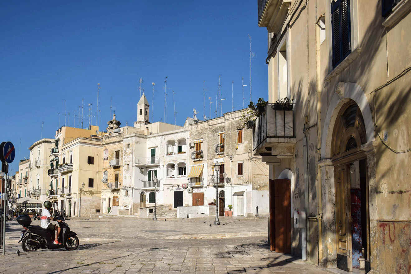 A person riding a scooter in a town square with lots of buildings around