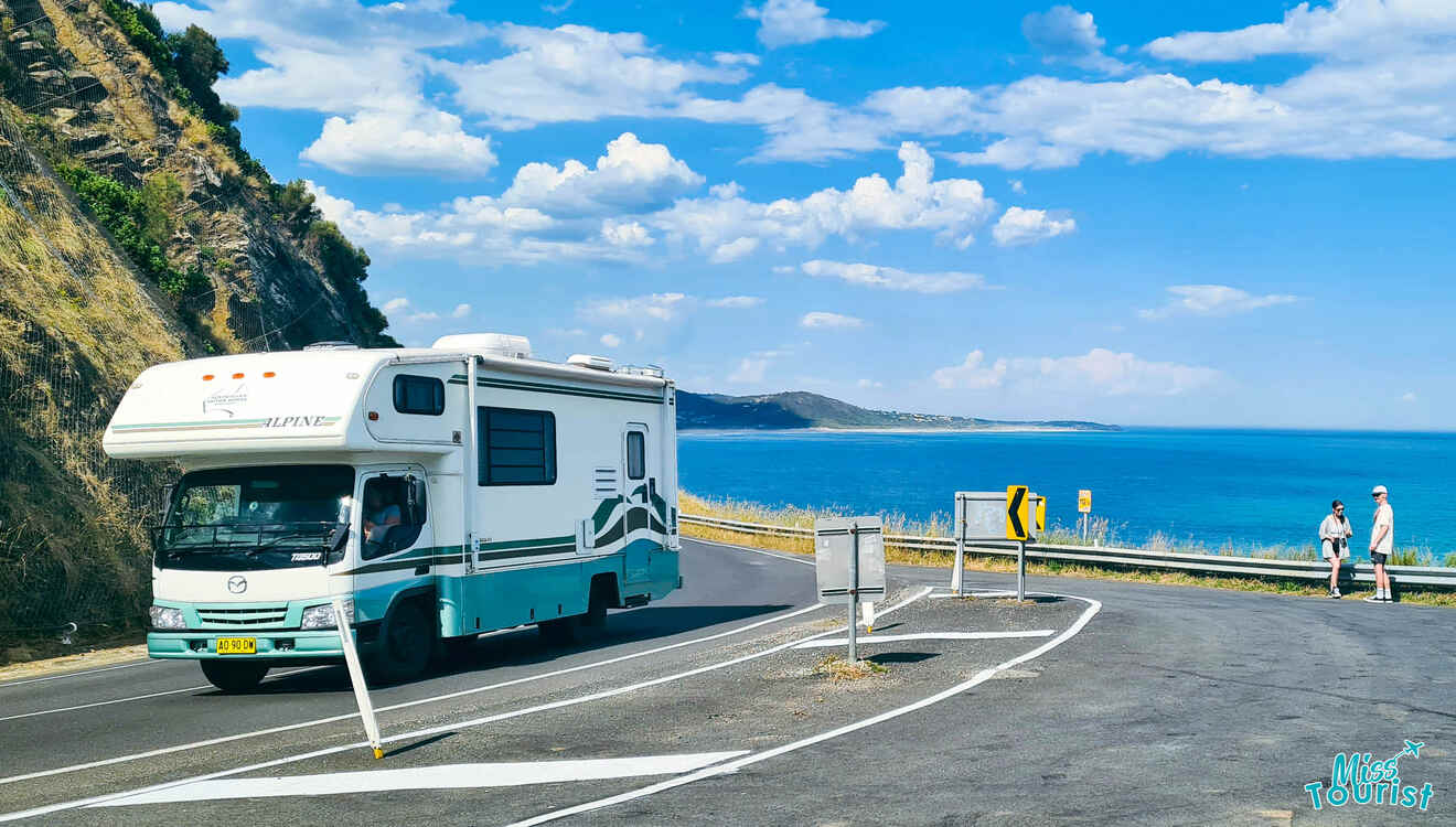 An rv is driving down a road near the ocean.