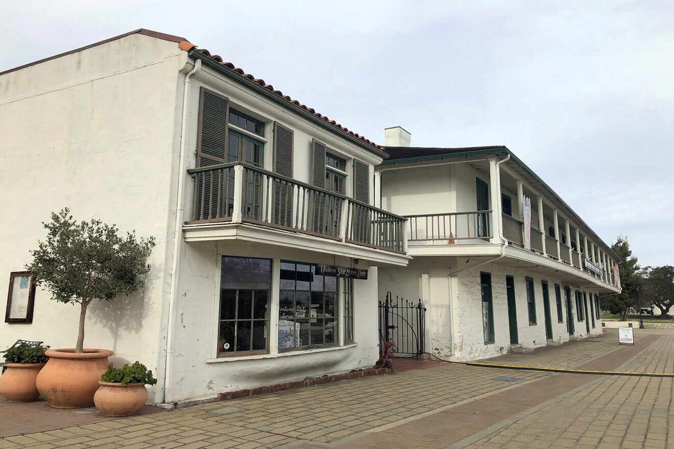 A white building with balconies and potted plants.