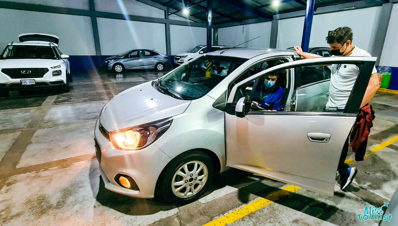 A man is opening the door of a car in a garage.