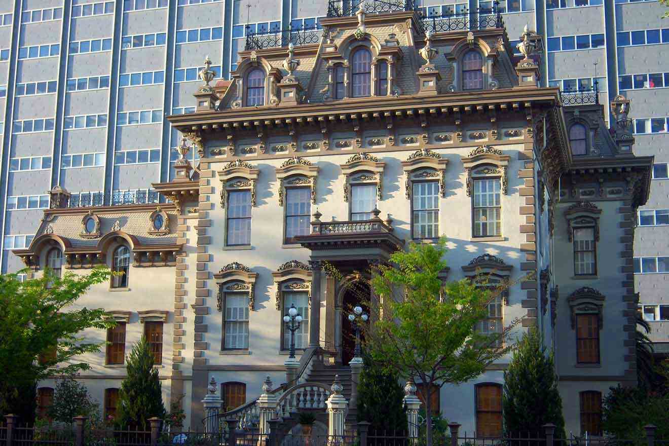 An ornate house in front of a tall building and trees in front of it