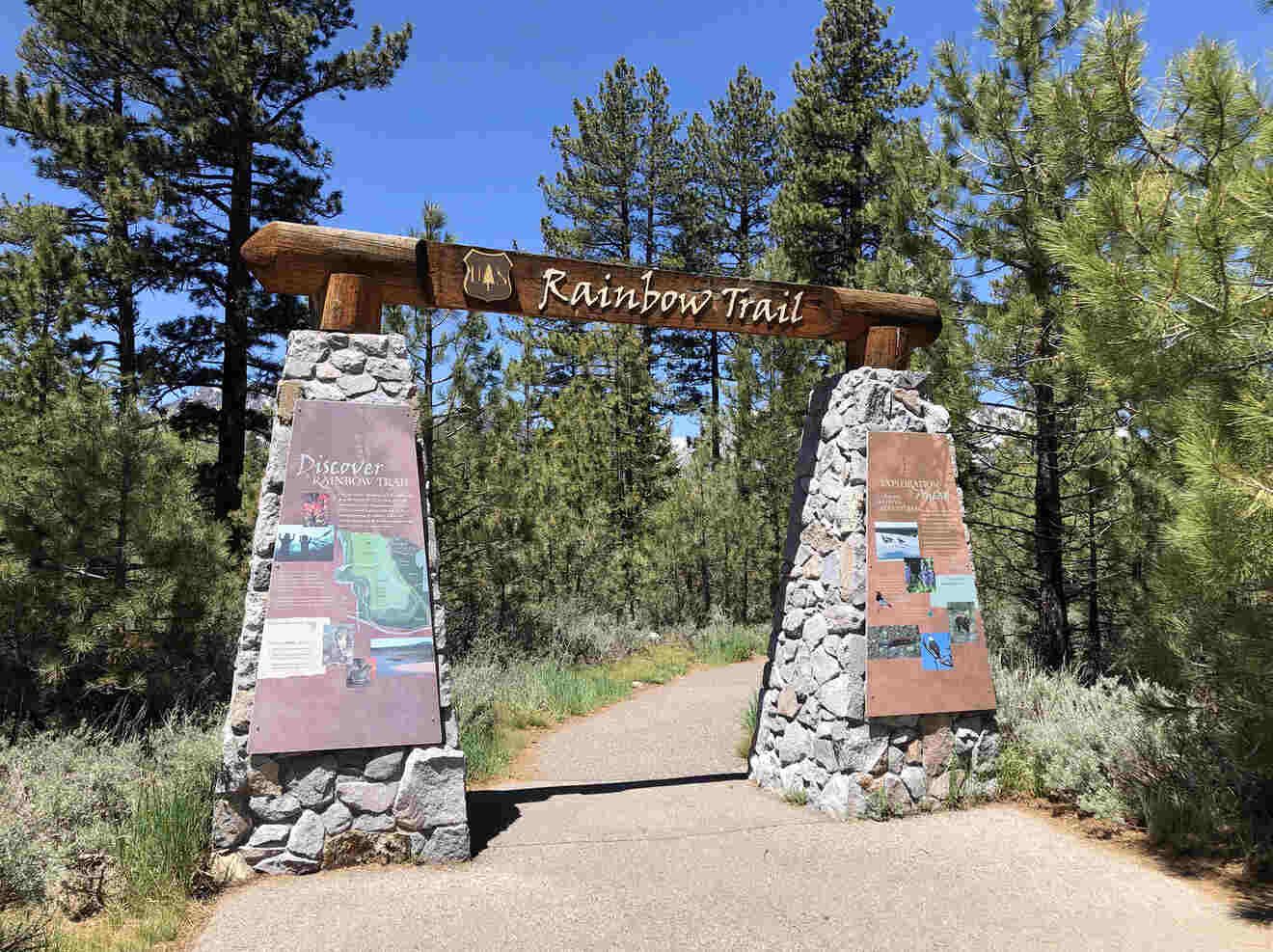 a gate made of stone and wood leading to a trail with posters on both sides