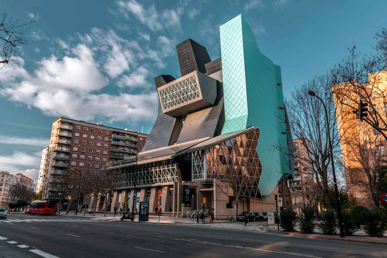 street view with a large building with a very unusual design on it's side and trees around it