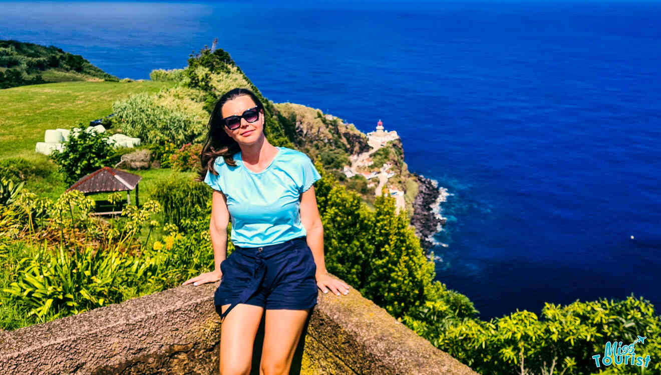 A woman sitting on a ledge overlooking the ocean.