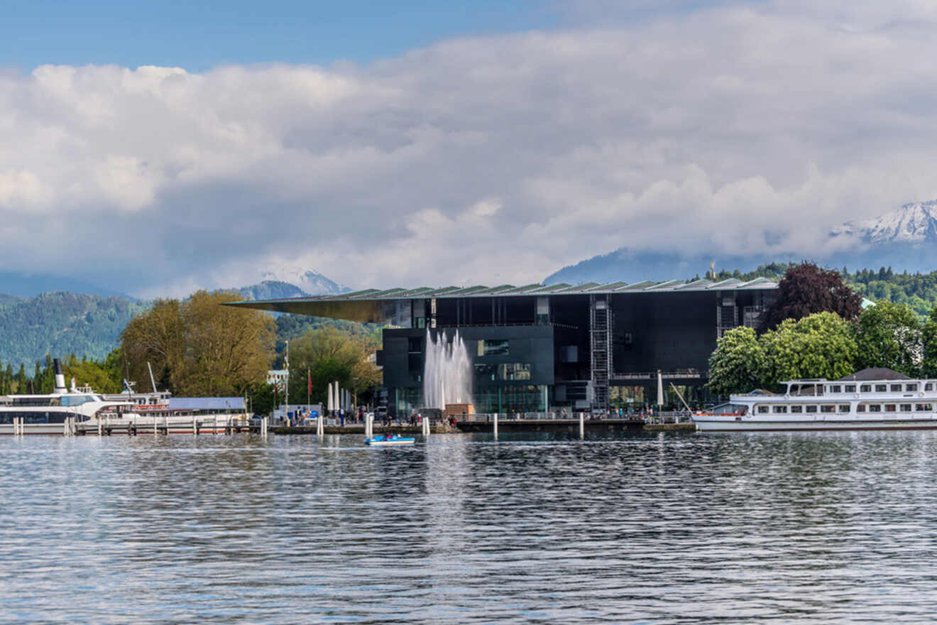 A boat docked in front of a building with mountains in the background.