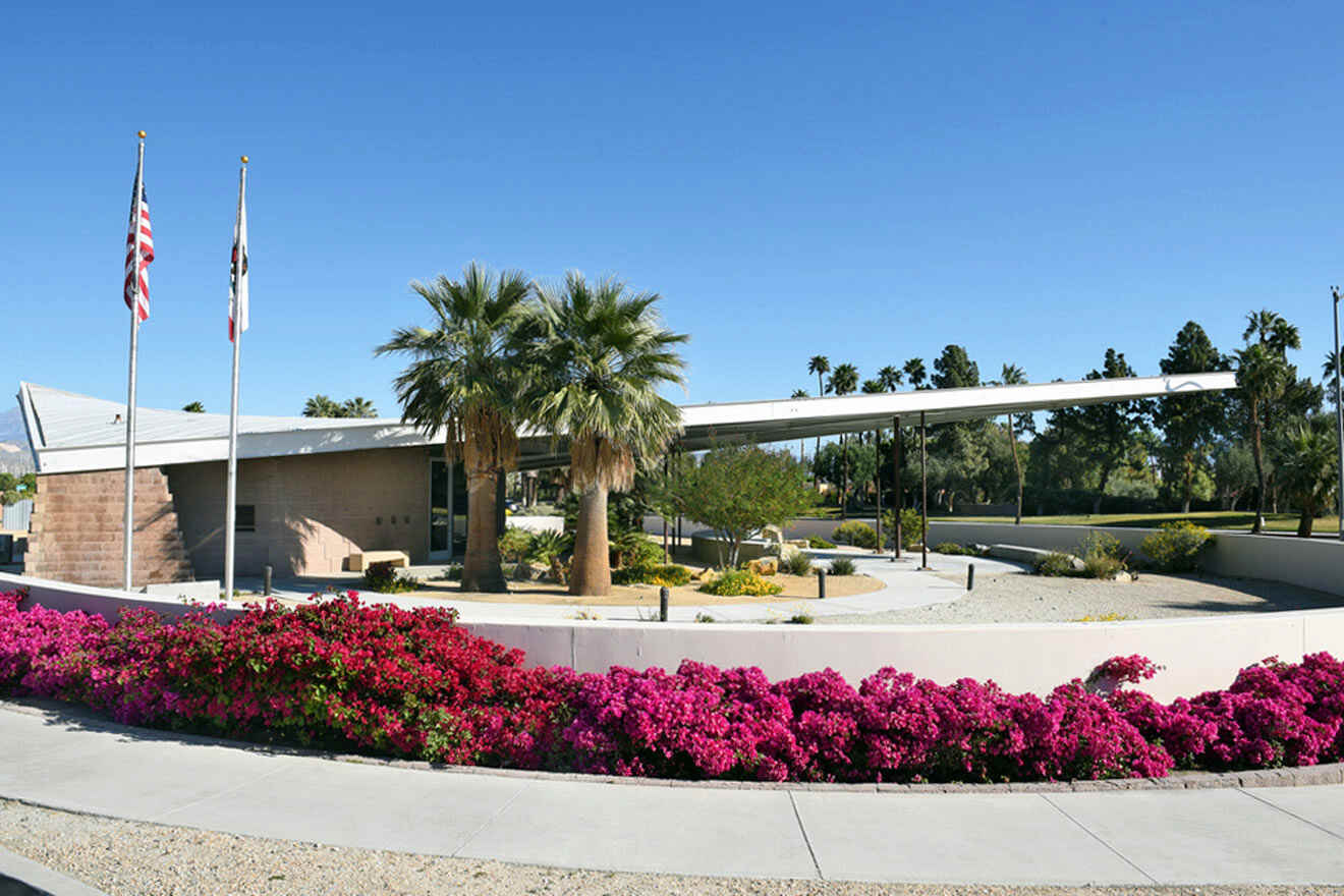 A building with palm trees and flowers in front of it.