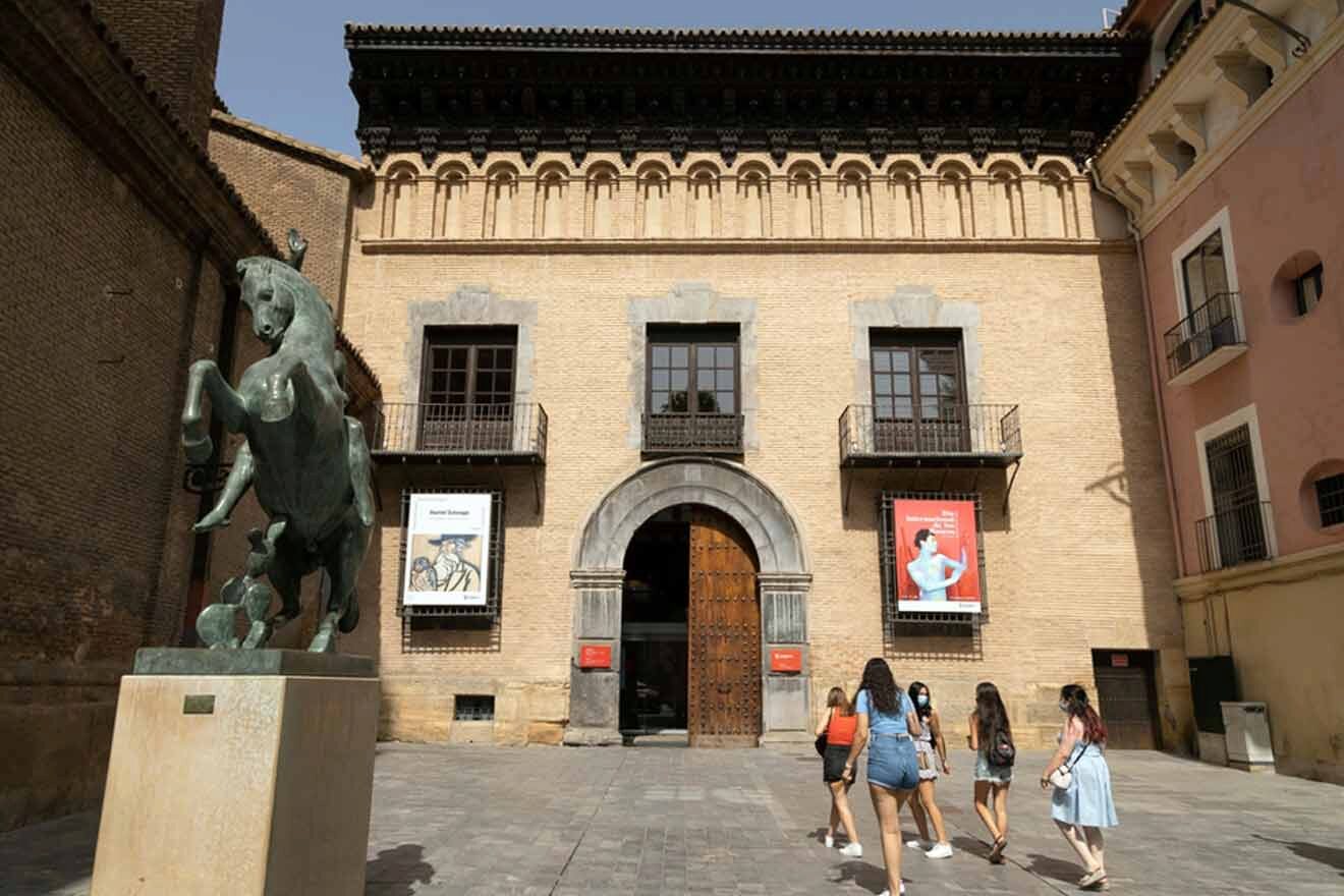 a statue of a horse is in front of a building with people walking towards the entrance