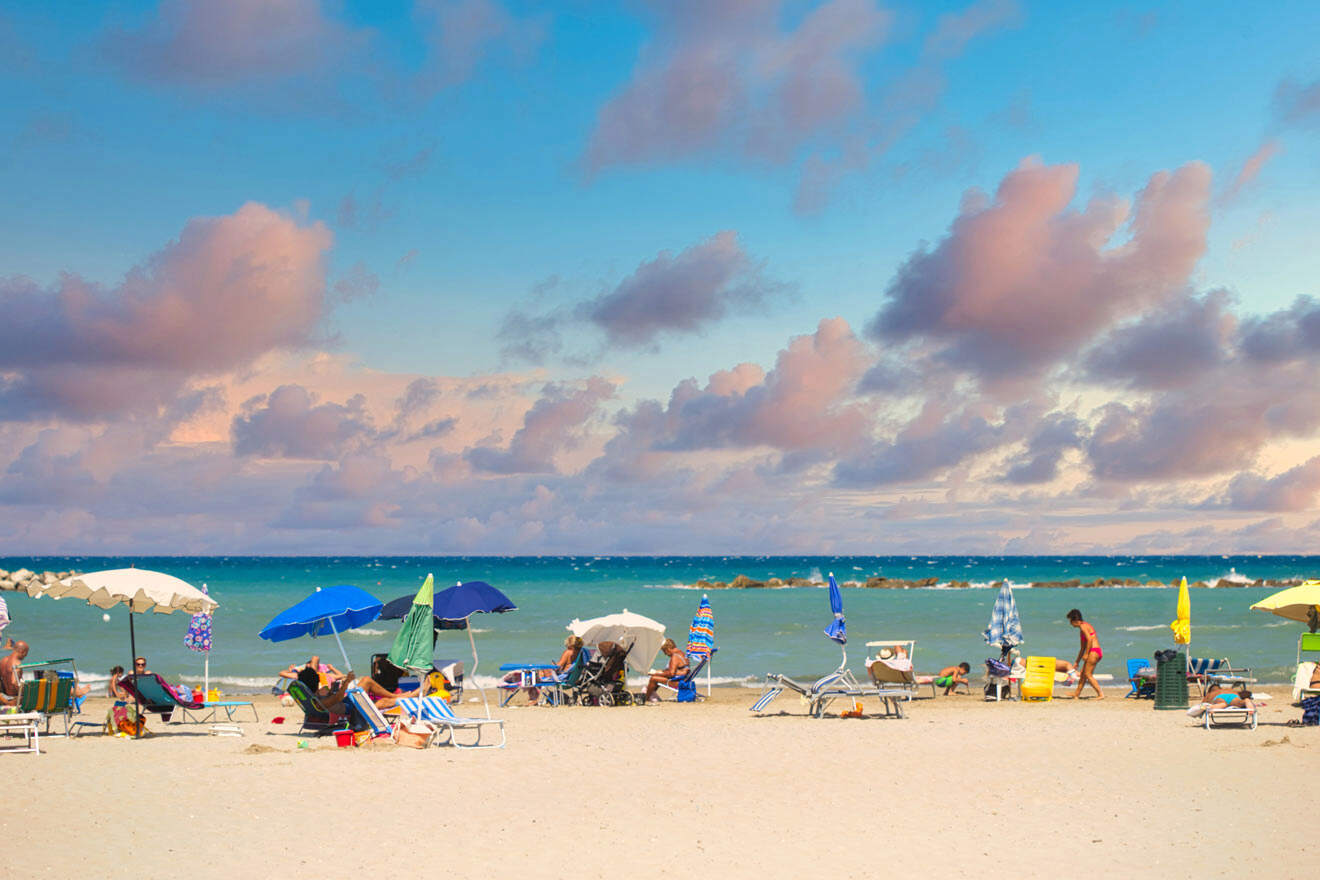 A group of people on a beach with umbrellas and sunbeds