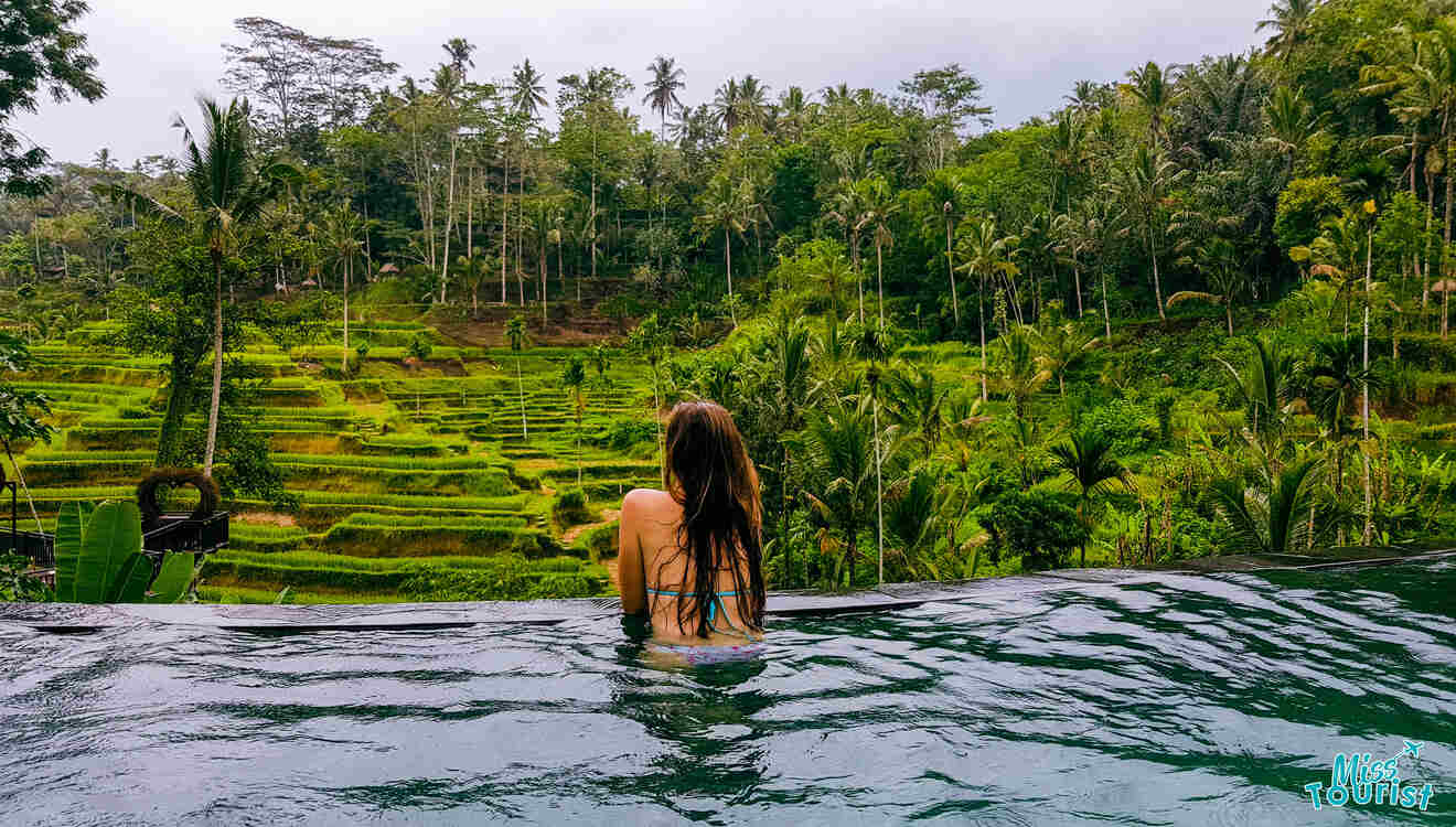 A woman in a pool overlooking rice terraces in bali.