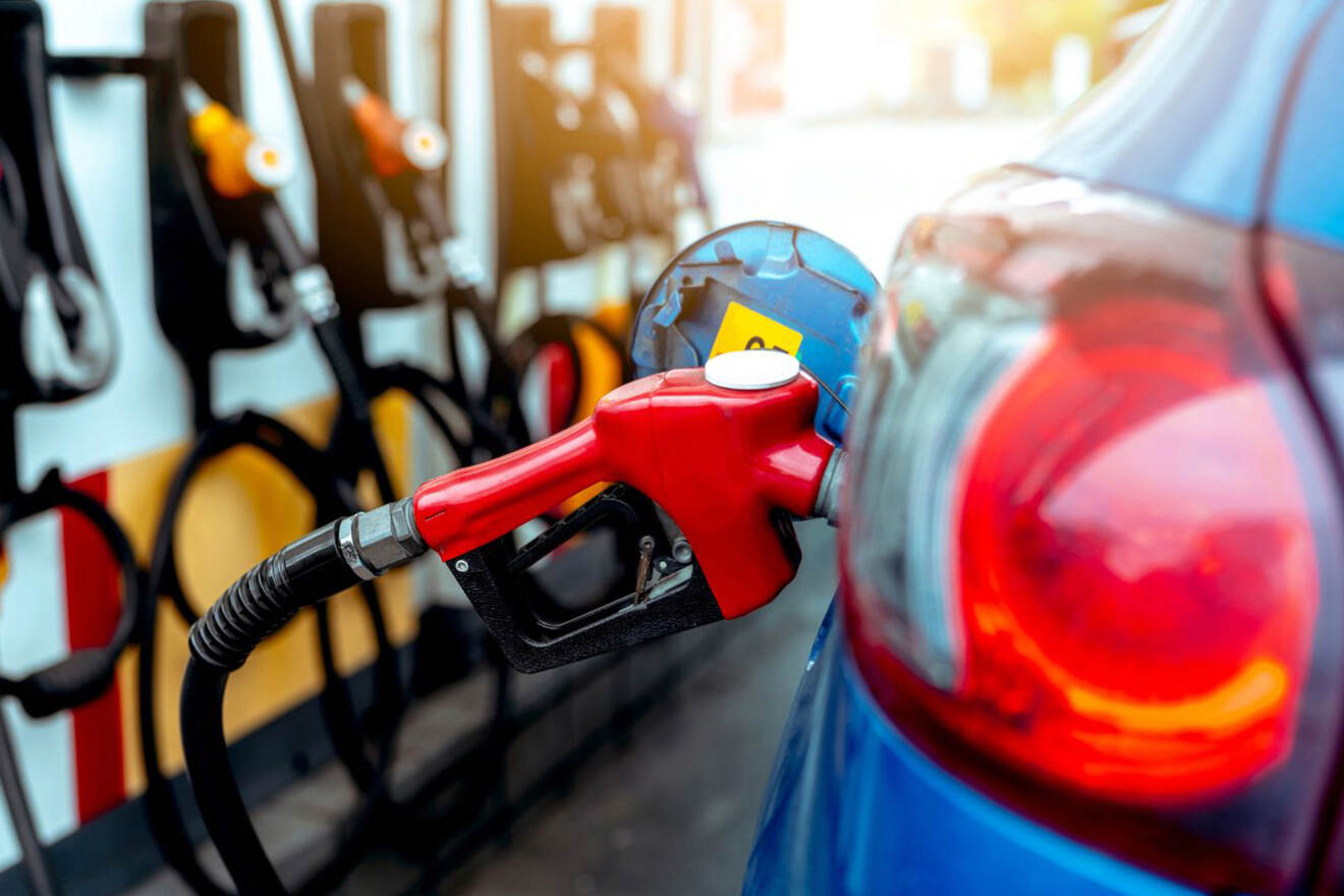 A blue car is filling up with gas at a gas station.