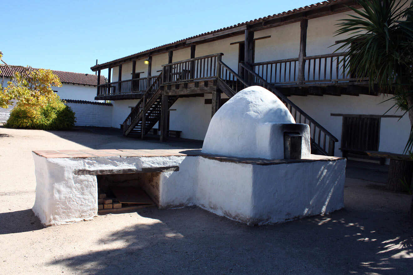 A white building with a brick oven in front of it.