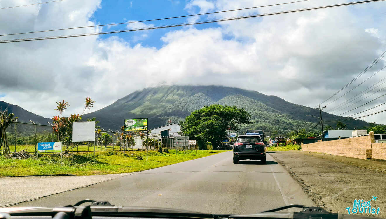 A car driving down a road with a mountain in the background.