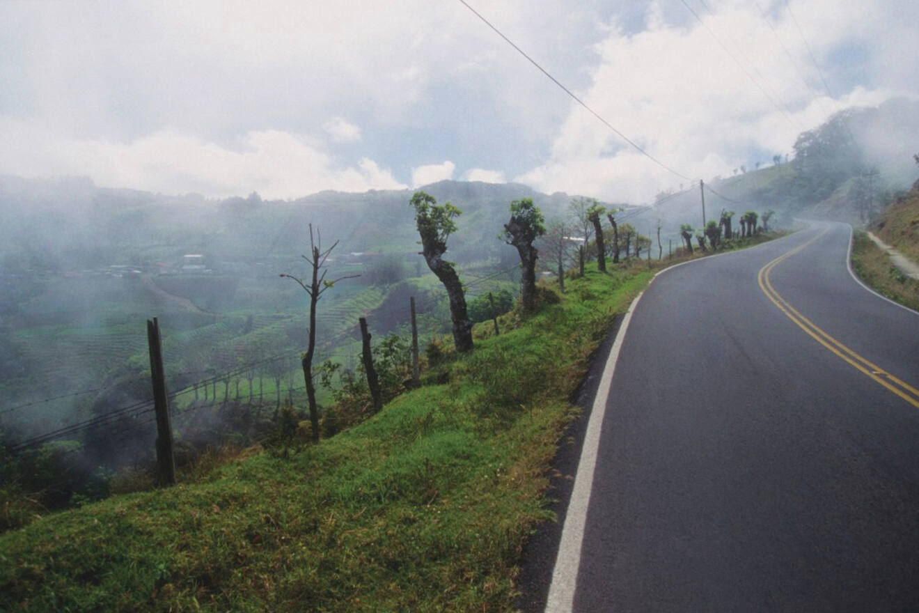 A winding road in a mountainous area with a cloudy sky.