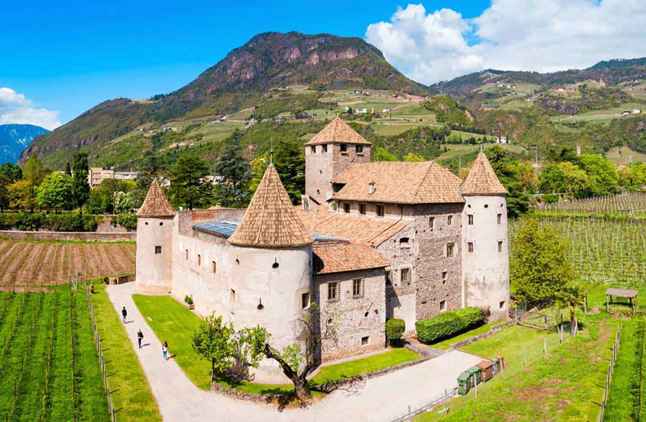 An aerial view of a castle surrounded by hills and mountains with lots of greenery