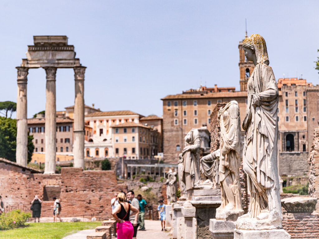 statues around a courtyard with temple ruins in the background