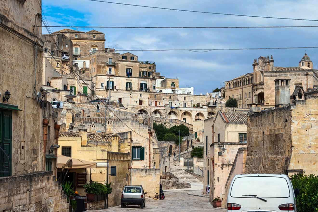 view of a cobblestone street with buildings and parked cars