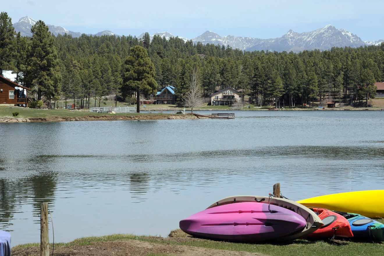 A group of canoes and kayaks on the shore of a lake.