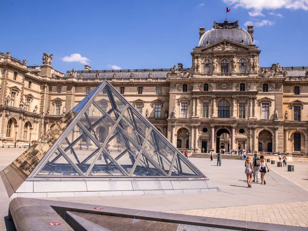 A glass pyramid and stone buildings in Paris