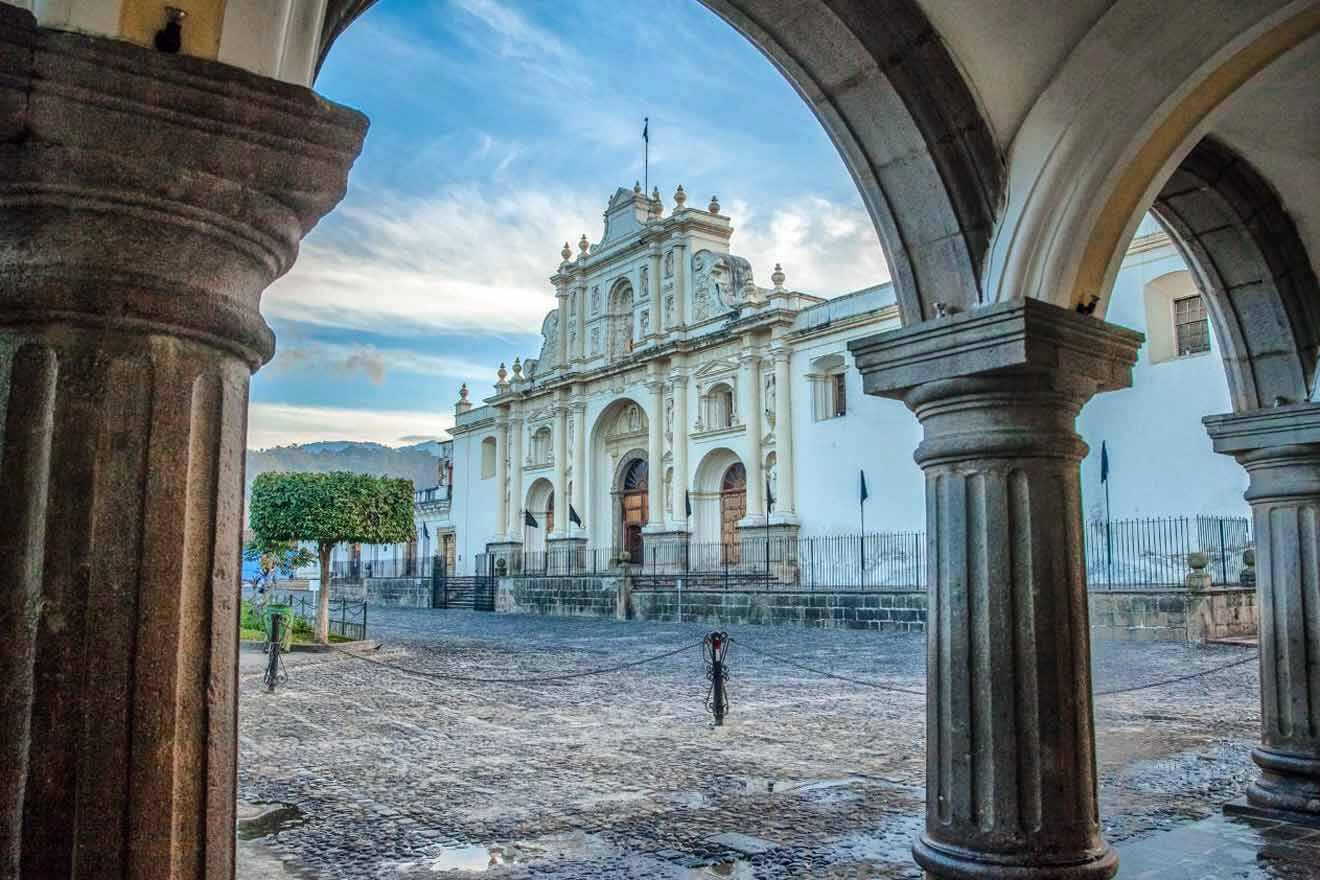 A courtyard with arches and a church in the background.