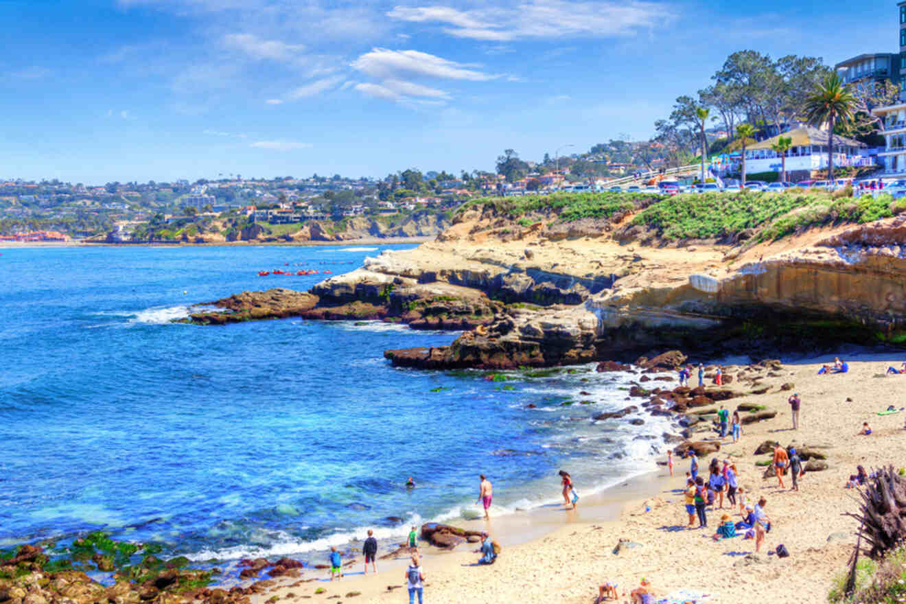 a group of people standing on top of a sandy beach and rocks