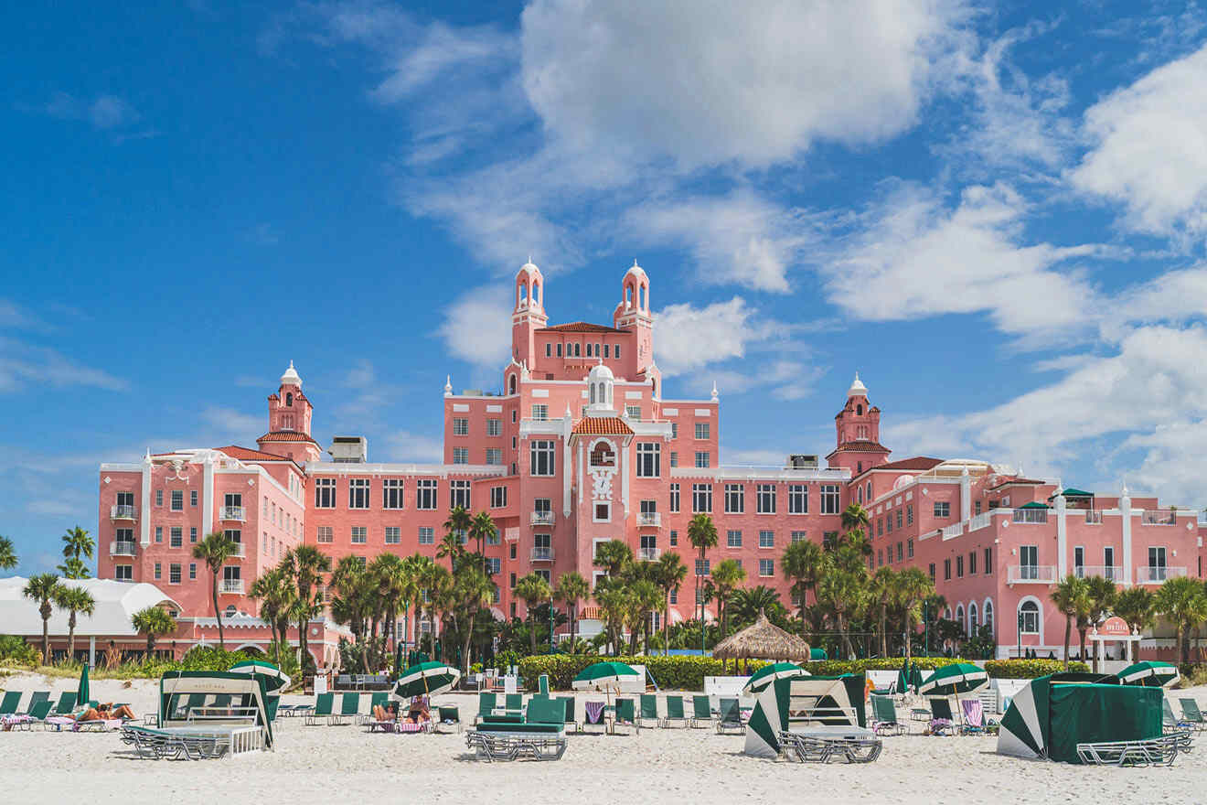 A pink building with lounge chairs on the beach.